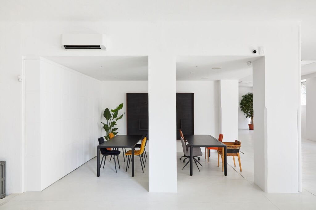 Bright minimalist office space with sleek tables and chairs, featuring natural plants.